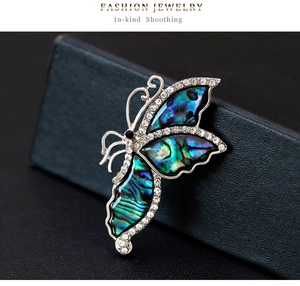 Detailed macro of a silver butterfly brooch with colorful abalone shell and rhinestones