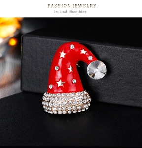 Macro shot of cartoon Santa hat brooch with red enamel and sparkling rhinestones
