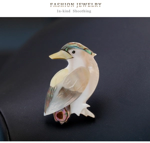 Gros plan de la broche oiseau avec texture nacre sur fond de cuir noir texturé