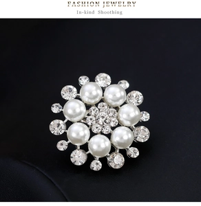 Macro shot of a floral pearl brooch with sparkling rhinestones on a black leather background