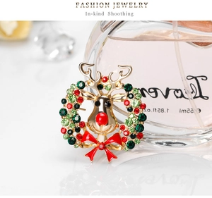 Détail d'une broche couronne de Noël avec tête de renne, cristaux rouges et nœud