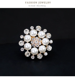 Macro shot of flower brooch with white pearls and sparkling crystal center on black background