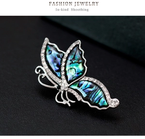 Macro shot of silver butterfly brooch with abalone shell inlay and white rhinestones