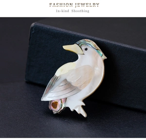 Détail d'une broche en forme d'oiseau avec texture en nacre irisée sur fond sombre