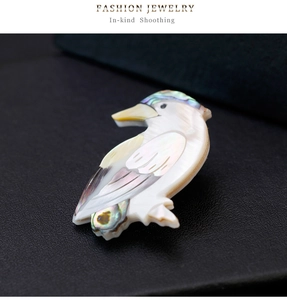 Vue rapprochée d'une broche oiseau en nacre naturelle avec des détails sculptés