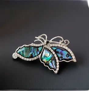 Macro detail of silver butterfly brooch with iridescent shell wings and sparkling rhinestones