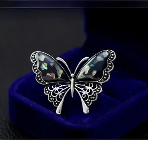 Detail of silver butterfly brooch with colorful shell inlay in a premium jewelry box