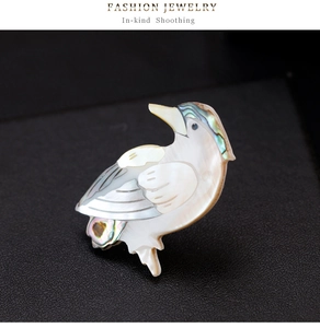 Détail macro d'une broche oiseau en nacre irisée et acier inoxydable poli brillant