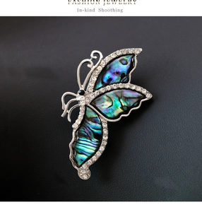 Macro shot of butterfly brooch with colorful abalone shell inlay and sparkling rhinestones