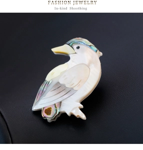 Détail d'une broche en forme d'oiseau avec nacre blanche et incrustations d'ormeau coloré