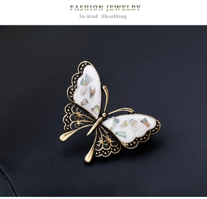 Detailed close-up of a vintage butterfly brooch with colorful shell inlays on black background