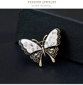 Detailed close-up of golden hollow butterfly brooch with white shell wing inlays