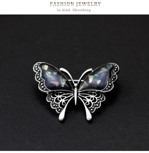 Detailed close-up of a butterfly brooch with shell inlay and vintage silver hollow patterns