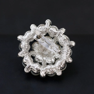 Vista posteriore di un'elegante spilla floreale con spillo in metallo argento e perle