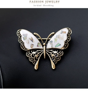 Close-up of butterfly brooch with shell inlay and intricate gold filigree metalwork