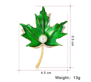 Détail d'une broche feuille d'érable en émail vert avec strass blancs et perle