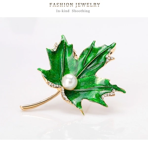 Détail de broche feuille d'érable en émail vert, avec des strass brillants et une perle