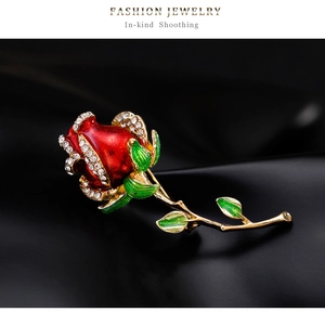 Détail macro d'une broche rose en émail rouge avec bord en cristal sur soie noire