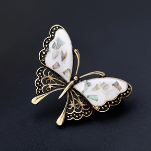 Elegant gold butterfly brooch with iridescent shell wings and filigree detail on black