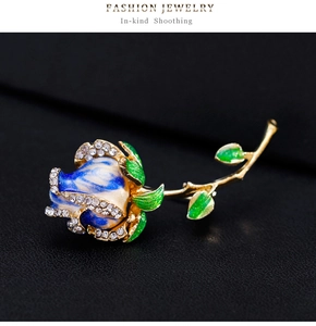 Macro d'une broche rose en émail bleu et blanc avec strass sur cuir noir texturé