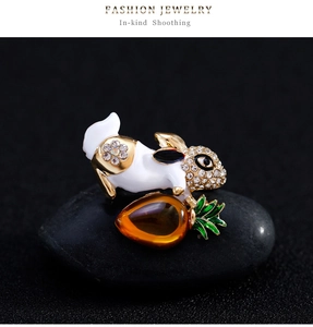 Détail macro d'une broche lapin en émail avec strass tenant une petite carotte