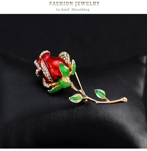 Détail d'une broche rose en émail rouge avec cristaux sur un coussin à bijoux noir