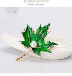 Détail de la broche feuille d'érable en émail vert avec cristaux et perle centrale