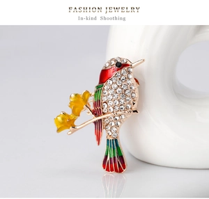 Close-up of vibrant enamel bird brooch with sparkling rhinestones on gold alloy base