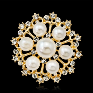 Broche fleur dorée élégante avec perles blanches et strass sur un fond noir réfléchi
