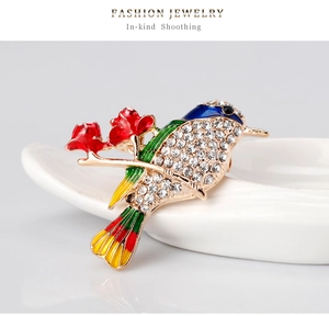 Detailed macro view of colorful enamel bird brooch with sparkling white zircons on a branch