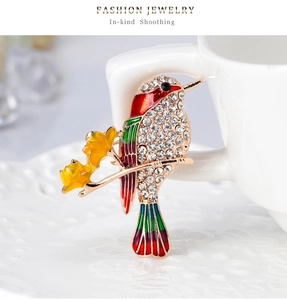 Detail of a bird brooch with colorful enamel wings and rhinestones on a golden twig