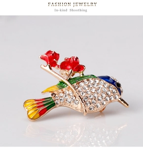 Detail of colorful bird brooch with sparkling rhinestones and enamel flower on a grey background