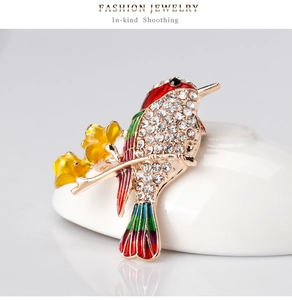 Detailed view of colorful enamel bird brooch with sparkling crystals on gold plating