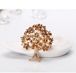 Dettaglio di una spilla dorata a forma di albero con strass color ambra scintillanti