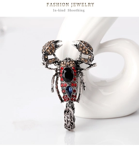 Macro shot of retro scorpion brooch with black gemstone and red crystal details