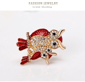 Close-up of owl brooch with red enamel and sparkling rhinestones on golden alloy