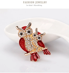 Macro shot of twin owls brooch with red enamel and crystals on gold branch