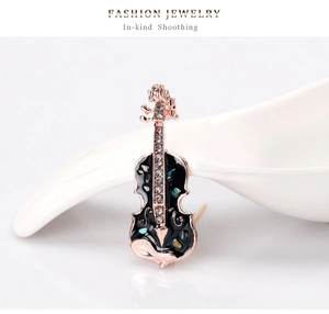 Vue macro d'une broche violon en or rose avec nacre, émail noir et strass brillants