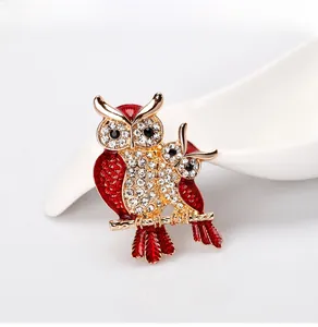 Detailed close-up of two red owl brooches with rhinestones on a golden tree branch