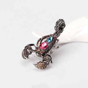 Vintage scorpion brooch with pink and blue gemstones and amber rhinestones on white