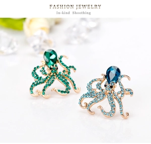 Detailed close-up of emerald green and deep blue rhinestone octopus brooches on gold
