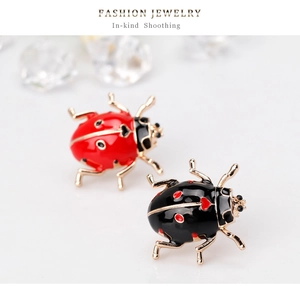 Detail of red and black ladybug stud earrings with gold finish and polished lacquer coating