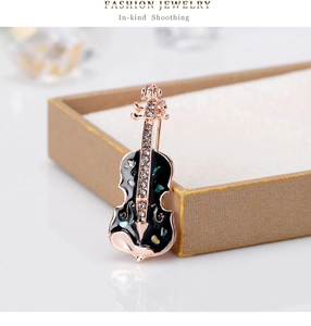 Vue macro de la broche violon avec émail noir, éclats de nacre arc-en-ciel et zircons