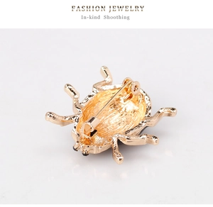 Close-up of golden beetle brooch back with pin clasp and wavy metal texture detail