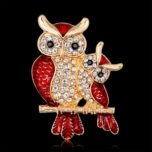 Elegant owl brooch with red enamel and crystals on a polished golden metal base