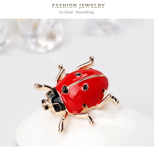Macro detail of a ladybug brooch with red enamel and heart patterns on a gold frame