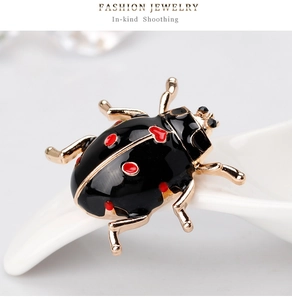 Macro shot of ladybug brooch with red heart enamel and black rhinestones on ceramic tray
