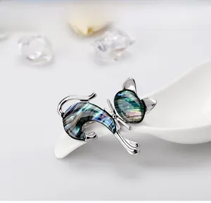 Macro shot of vintage silver cat brooch with iridescent shell inlay on white spoon