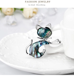 Macro shot of a vintage cat brooch with iridescent shell inlay on a white porcelain plate