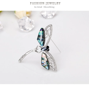 Detailed macro view of dragonfly brooch with iridescent shell wings and sparkling crystals